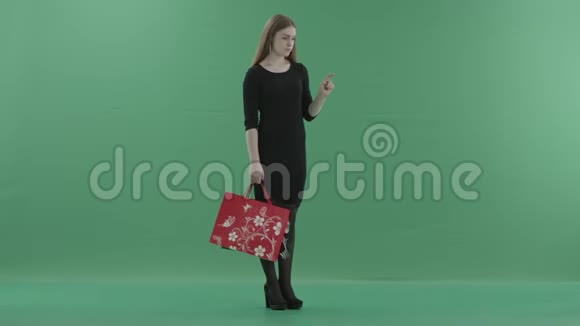 美丽的女人穿着黑色的小连衣裙手里拿着购物袋在数字屏幕上滚动她站在右边视频的预览图