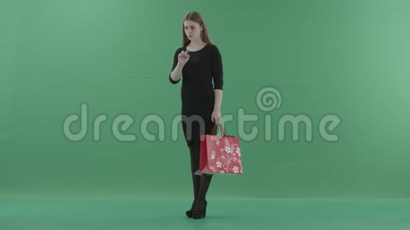 美丽的女人穿着黑色的小连衣裙手里拿着购物袋在数字屏幕上滚动她站在左边视频的预览图