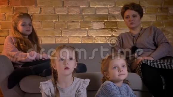 在舒适的家中白种人的母亲和三个女儿坐在一起专心看电影的特写镜头视频的预览图