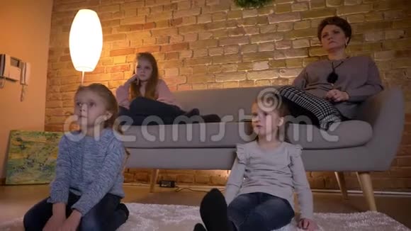 白种人母亲的家庭肖像三个女儿在舒适的家庭氛围中交流和观看电影视频的预览图