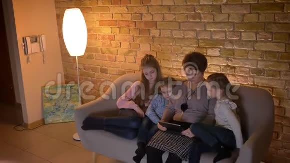 白种人的母亲和三个女儿在观看平板电脑时表现出了极大的关注和对舒适家庭的兴趣视频的预览图