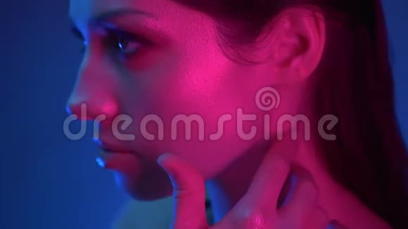 蓝粉色霓虹灯闪烁妆的模特特写镜头用手指摆成镜头遮住她的脸视频的预览图