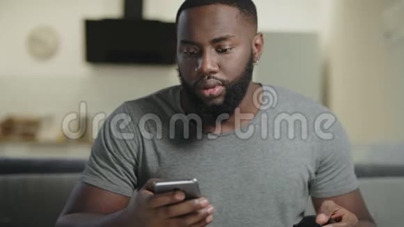 黑人在开放式厨房拿着电话专心致志的家伙在智能手机里发短信视频的预览图