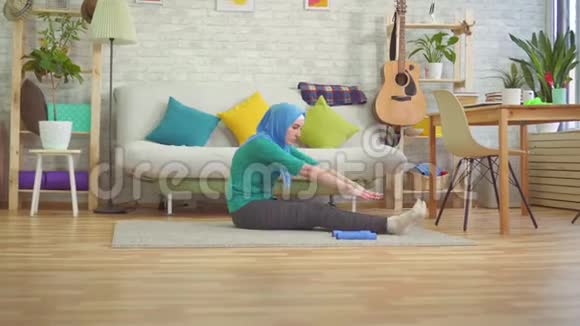 穿着头巾在现代公寓里做热身运动的穆斯林女人视频的预览图
