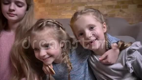 三个小白种人女孩在舒适的家庭氛围中快乐地拥抱在一起的肖像视频的预览图