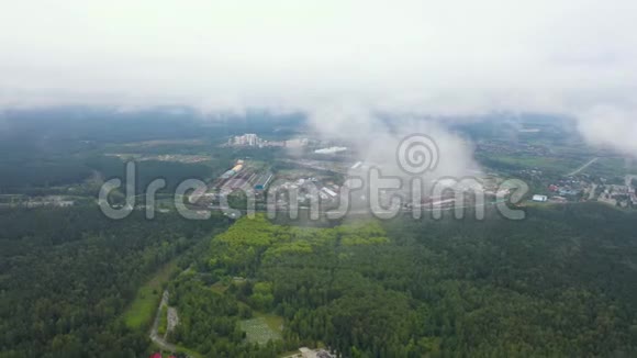 在新鲜的早晨空中飞行在云上工业区周围是森林视频的预览图