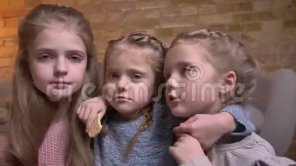 三个小白种人女孩在舒适的家庭氛围中快乐地拥抱在一起的肖像视频的预览图