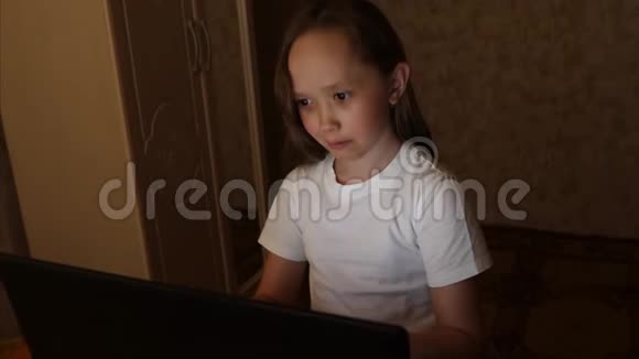 女孩晚上在用笔记本电脑读电子书儿童坐在社交网络的电脑和检查电子邮件视频的预览图