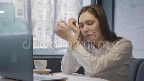 肖像悲伤的年轻女人用她的笔记本电脑坐在咖啡馆的桌子上坐在靠近窗户的沙发上工作的女孩视频的预览图