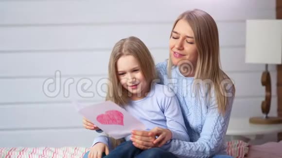 幸福的妈妈和可爱的女儿带着红心看着创意礼品手工明信片视频的预览图