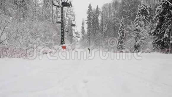 在冬季雪林滑雪道上的两个座位缆车的底部视图从滑雪坡上方爬升视频的预览图