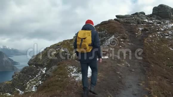 人在日落时在山峰上缓慢行走挪威欧洲穿着夹克戴着红帽子戴着黄色的视频的预览图
