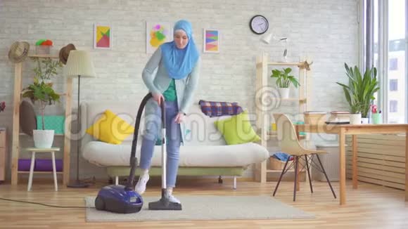 穆斯林妇女戴头巾用吸尘器打扫房间视频的预览图