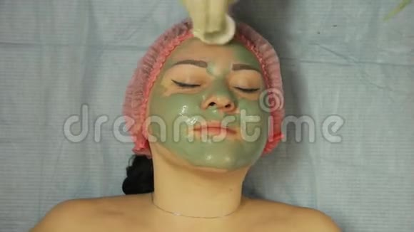 戴手套的美容师用棉碟从女人脸上摘下面具视频的预览图