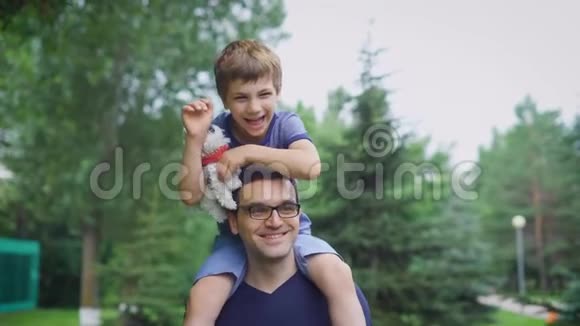 穿着蓝色衬衫的帅哥和他的儿子在街上散步男家长向儿童展示城市景观坐着的男孩视频的预览图