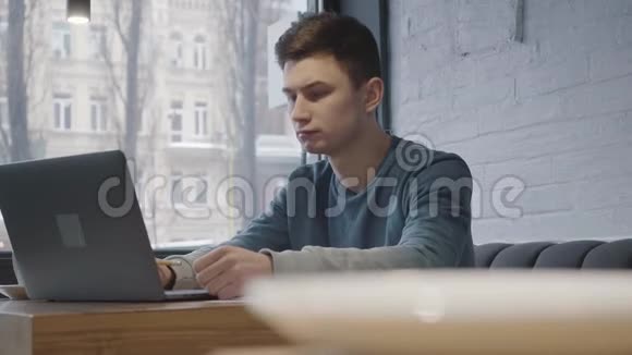 咖啡杯站在前台的桌子上坐在窗户附近的一个年轻人视频的预览图