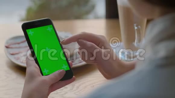 女商人在咖啡馆里使用带有绿色触摸屏的手机格林斯克莱恩视频的预览图