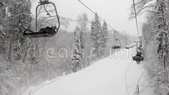 冬季雪林滑雪道上两座缆车的鸟瞰图从滑雪坡上方爬升视频的预览图