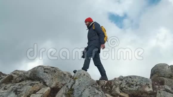 人在日落时在山峰上缓慢行走挪威欧洲穿着夹克戴着红帽子戴着黄色的视频的预览图