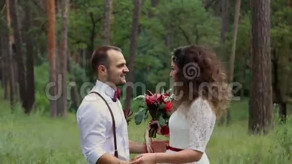 美丽的年轻夫妇在波西米亚风格的时尚森林看着对方的眼睛视频的预览图