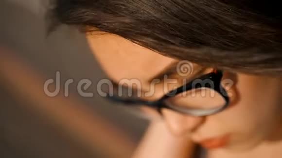一个戴眼镜的年轻女孩坐在台阶上女孩特写的肖像视频的预览图