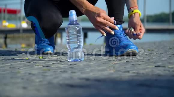 女跑步者准备用黄色智能手表系跑鞋的特写镜头视频的预览图
