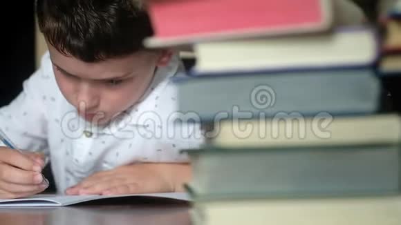 男孩蓝笔写在笔记本上解决课堂上的问题视频的预览图