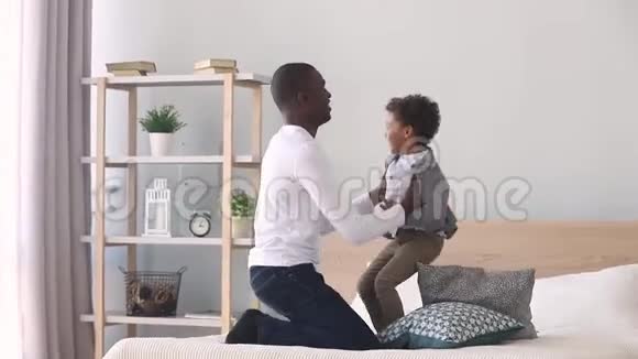 快乐的儿子跳着和黑爸爸在床上玩耍视频的预览图