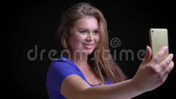 一位中年白种人深色头发的女性特写照片她在电话中打了个视频电话用手打招呼然后视频的预览图