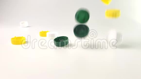 彩色塑料盖子掉在白色背景的桌子上视频的预览图