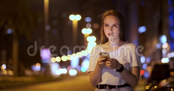 城市中的年轻女性通过智能手机拨打出租车视频的预览图