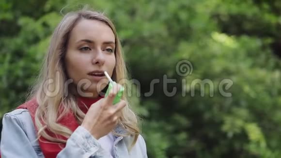 年轻的女人用喉咙喷雾站在公园的背景上健康和医疗理念视频的预览图