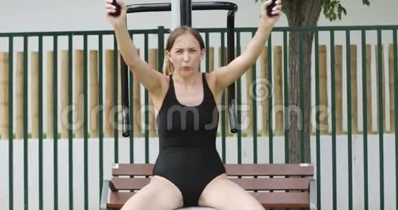 一个强壮的女人在公园的模拟器上做运动视频的预览图