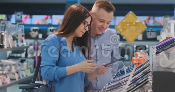 年轻漂亮的已婚夫妇一个穿着衬衫的男人和一个戴着智能手机的女人站在展示台旁视频的预览图