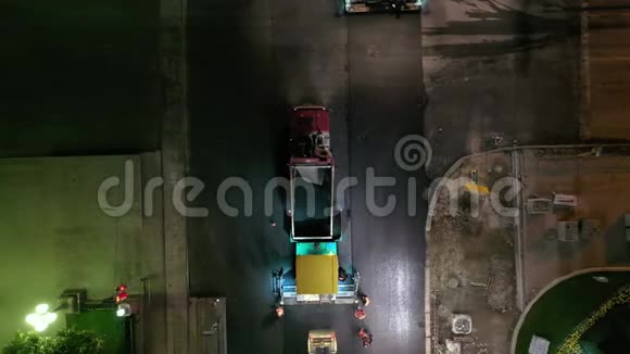 压路机在城市十字路口夜间整平新鲜沥青路面视频的预览图