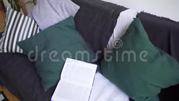 模糊概念沙发有枕头和温暖颜色的毯子一本书和一个格子特写视频的预览图
