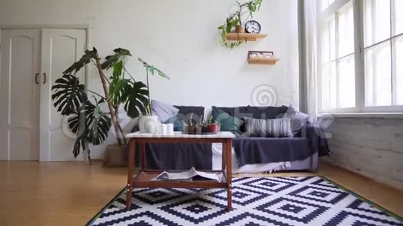 一张漂亮的地毯一张带杂志的小桌子一张靠在白色墙壁上的舒适沙发阁楼公寓视频的预览图