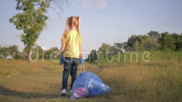 爱护自然生态可爱的小女孩根据指向垃圾桶的指示标志在路上拉一个带垃圾的大垃圾袋视频的预览图