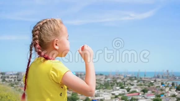 小女孩在城市和大海的背景上吹肥皂泡视频的预览图