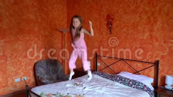 快乐的孩子跳到床上那个留着长发的女孩高高地跳起来大笑起来视频的预览图