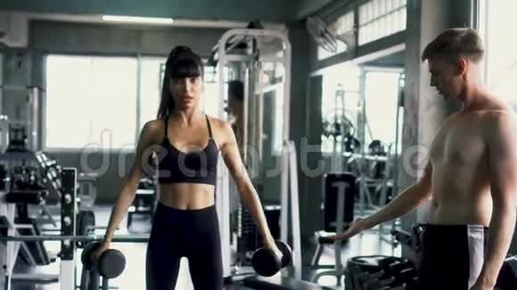 苗条的女人在健身房和她的私人教练一起做侧方的锻炼视频的预览图