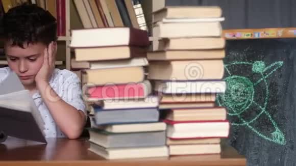 这个男孩在一堆书中读着一本厚厚的书和思念视频的预览图