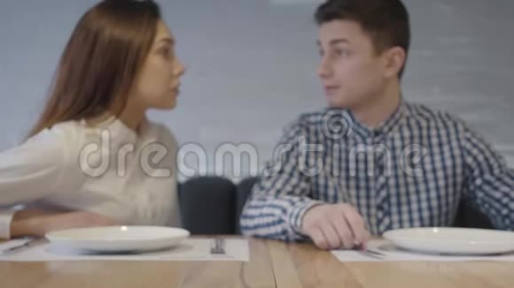 肖像正面有趣的一对夫妇饶有兴致地看着站在他们面前的桌子上的视频的预览图