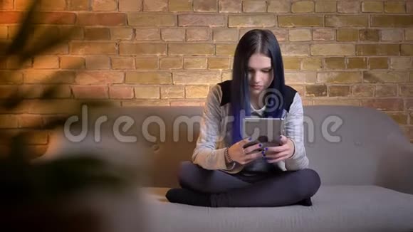 年轻漂亮的白种人女性的特写镜头她用平板电脑染了头发坐在上面开心地笑着视频的预览图