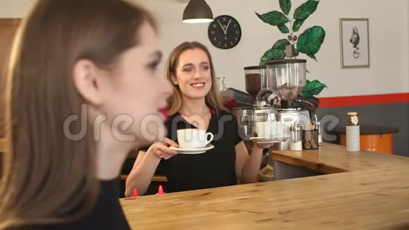 微笑的咖啡师女孩在咖啡店里为一对年轻夫妇提供一杯咖啡视频的预览图