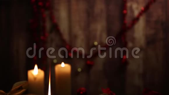 圣诞节的气氛三支点燃的蜡烛一支在前景上有大火焰的蜡烛红色和金色的脱钩的球缎子的金丝带视频的预览图