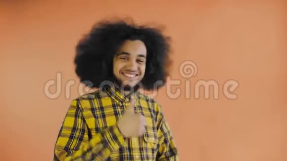 年轻快乐的美国黑人男子微笑同时竖起大拇指在橙色背景情感概念视频的预览图