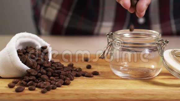 男人把烤好的咖啡豆从手里扔进罐子里用白色的袋子靠近4K视频的预览图