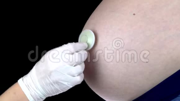 医生用听诊器听孕妇的腹部一个大肚子的年轻女子被视频的预览图