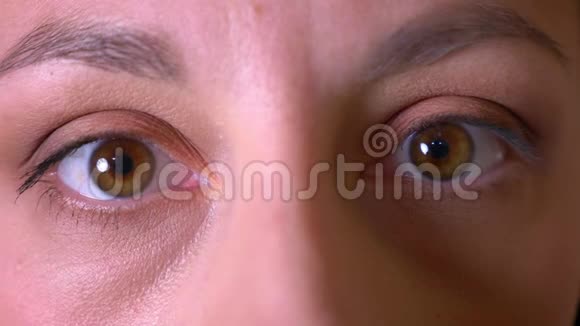 年轻女性脸上的特写镜头棕色眼睛用微笑的面部表情看镜头视频的预览图